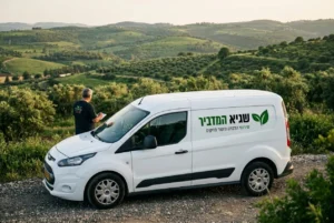 תמונה של הרכב המסחרי של 'שגיא המדביר' עם הלוגו, חונה על רקע נוף גלילי ירוק.